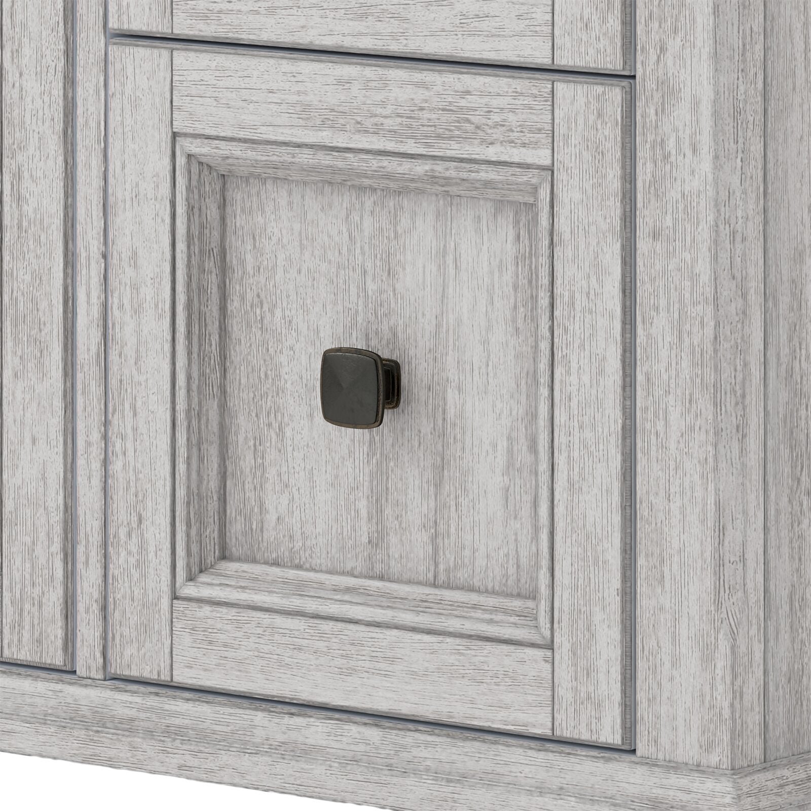 Close-up of a whitewashed solid wood bathroom vanity door with recessed paneling and a small square dark metal knob.