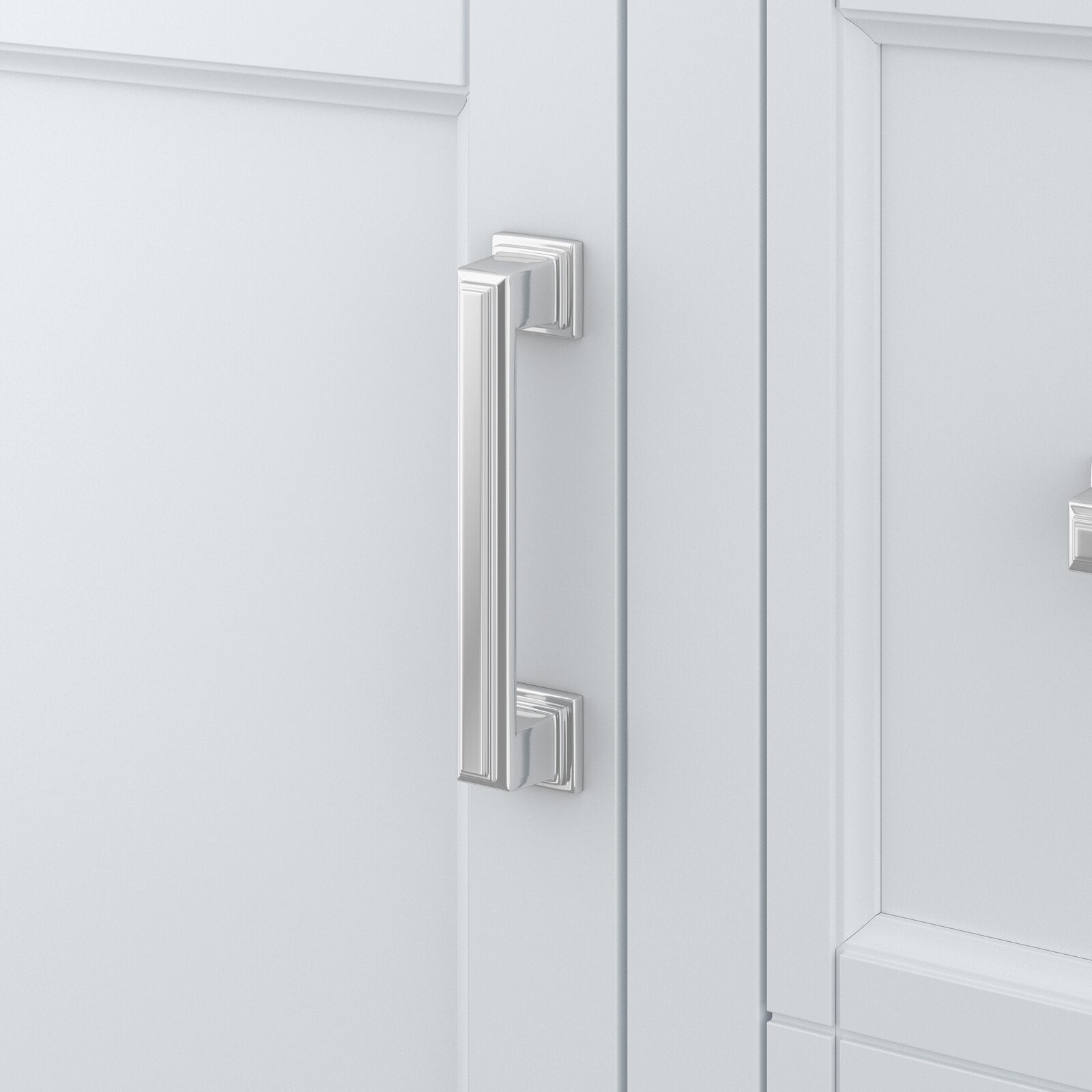 Close-up of a polished metal rectangular pull on a white solid-wood bathroom vanity door with recessed paneling and decorative square backplates in a modern contemporary style.