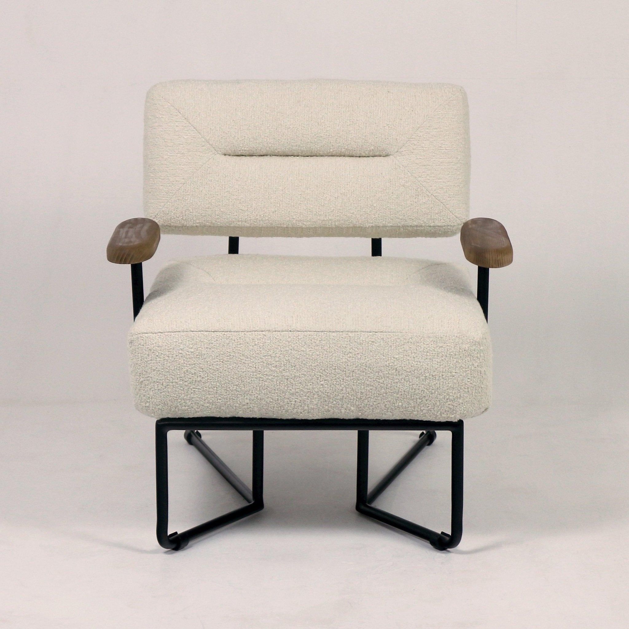 Front-facing modern lounge chair upholstered in cream boucle fabric with rounded walnut-toned wooden arm pads and a black metal sled-style base, mid-century modern inspired silhouette.