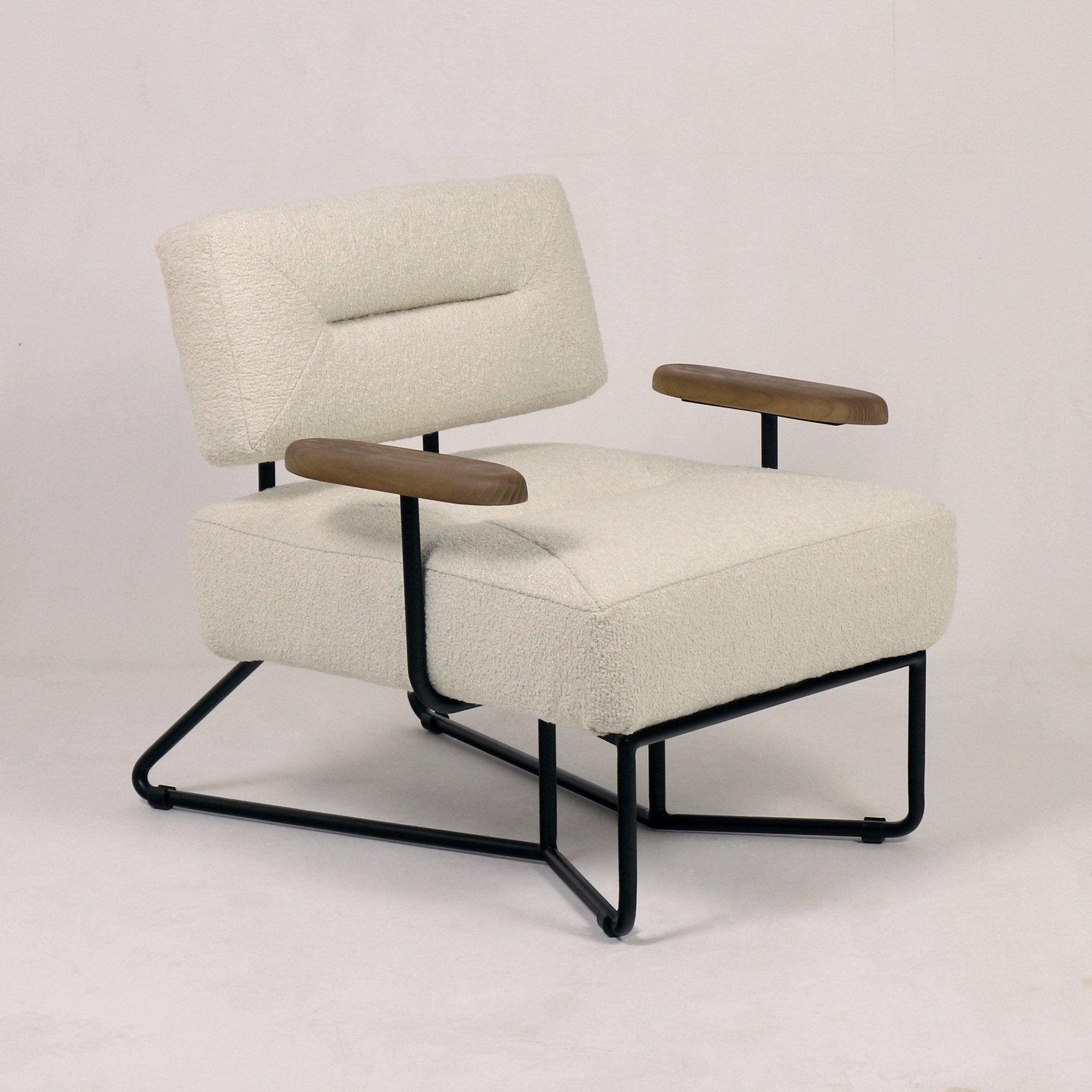 Low-back lounge chair upholstered in cream textured fabric with a tufted seat, walnut-finish wooden armrests and black powder-coated metal sled base in a modern mid-century silhouette.