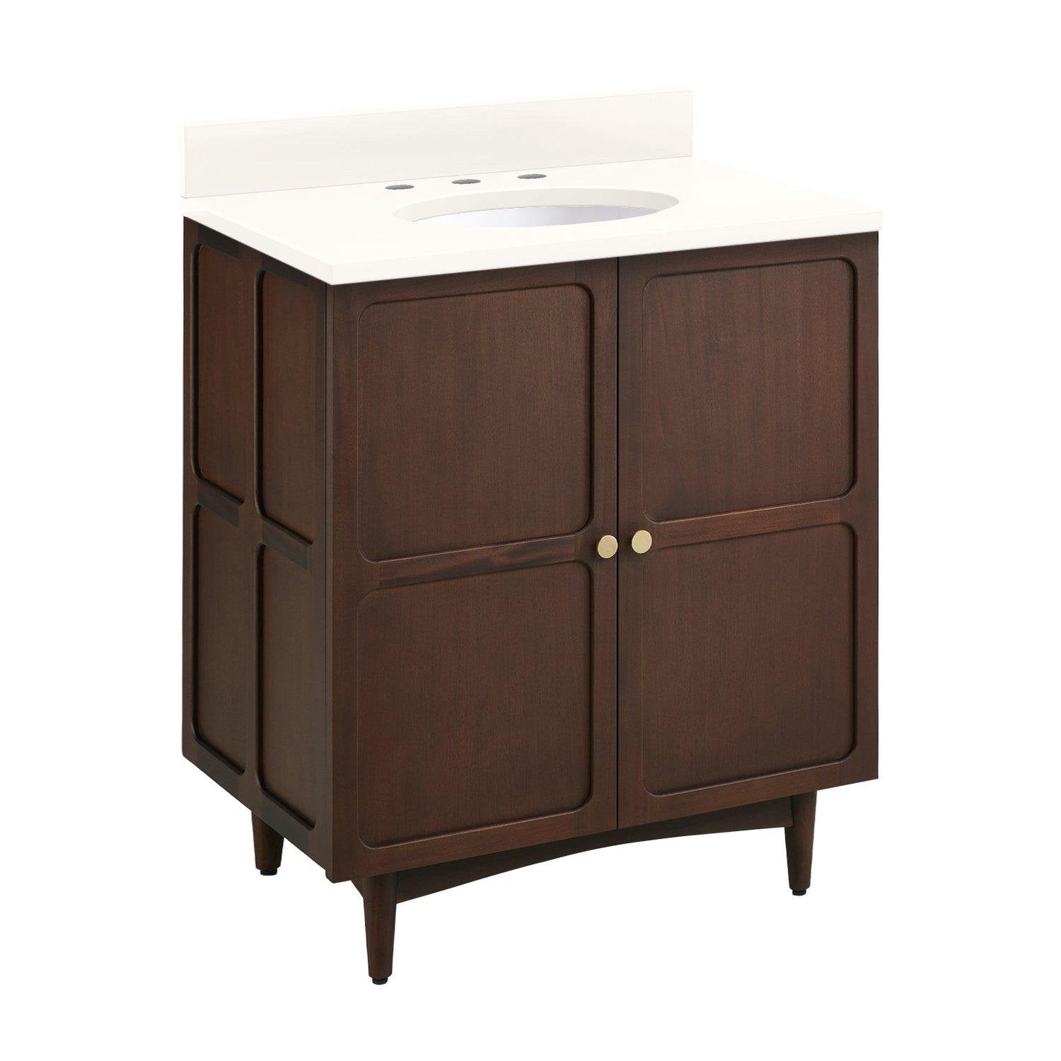 Freestanding coastal-style single-sink bathroom vanity in dark solid wood with a white stone countertop and backsplash, oval sink cutout, two recessed-panel doors, small round brass knobs and tapered legs.