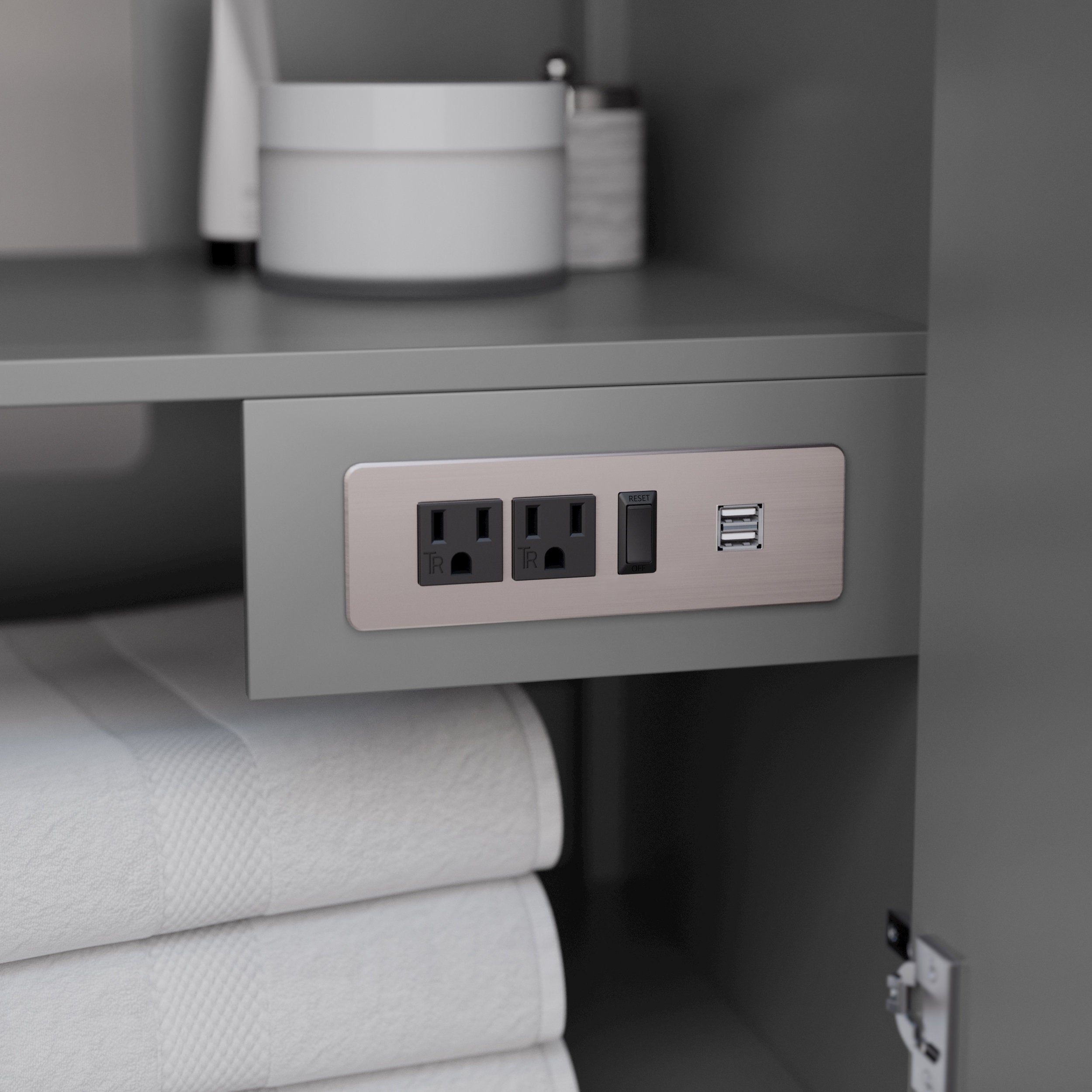 Interior view of a stone-colored modern vanity shelf showing a brushed-metal outlet plate with two grounded GFCI sockets, a reset switch and two USB charging ports above folded white towels.