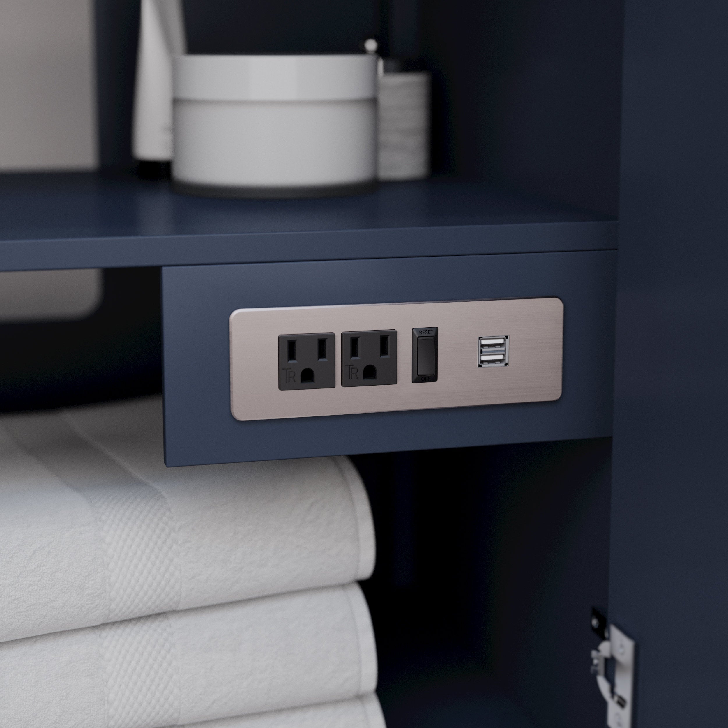 Close-up of a modern solid wood bathroom vanity interior in stone finish featuring a brushed metal power plate with two electrical outlets, a reset switch and dual USB ports mounted above folded white towels.