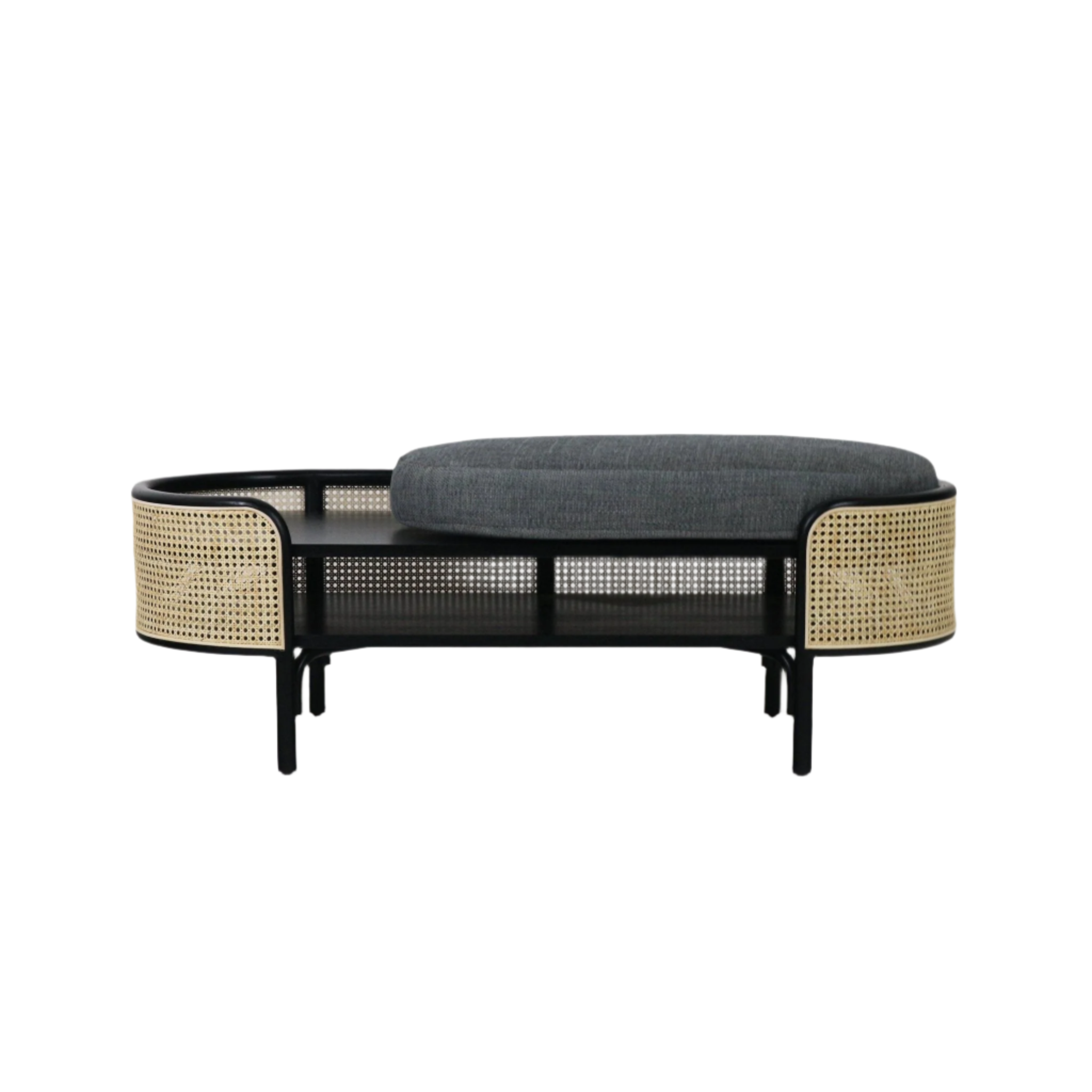 Boho-style low bench with a black solid wood frame, curved natural rattan cane panels and a thick gray upholstered cushion sitting over a slatted shelf, ideal for bedroom or entryway seating.