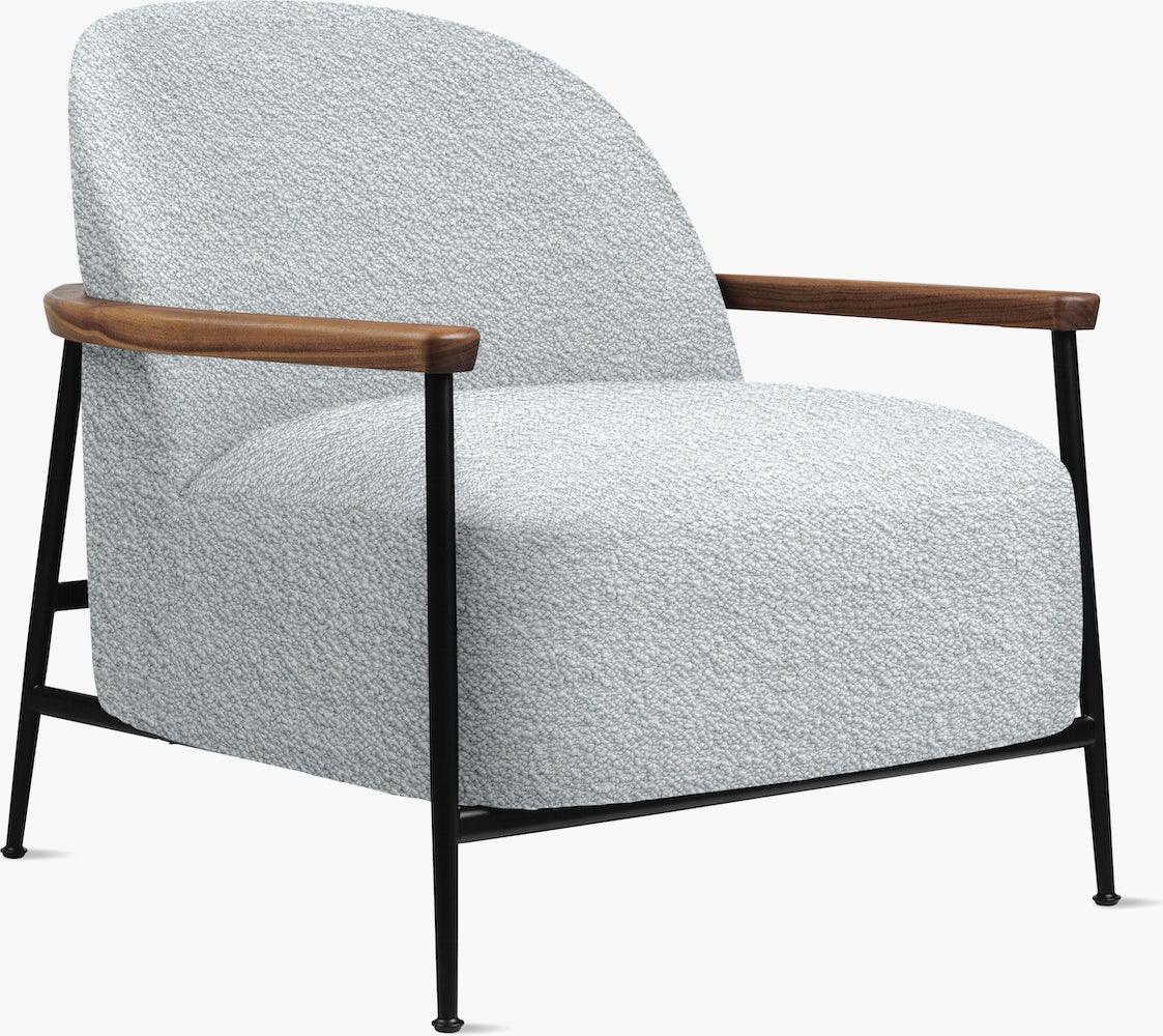 Light grey boucle upholstered accent chair with rounded back and deep seat, set on a slim black metal frame with tapered legs and warm wooden armrests, finished in a modern contemporary lounge style.