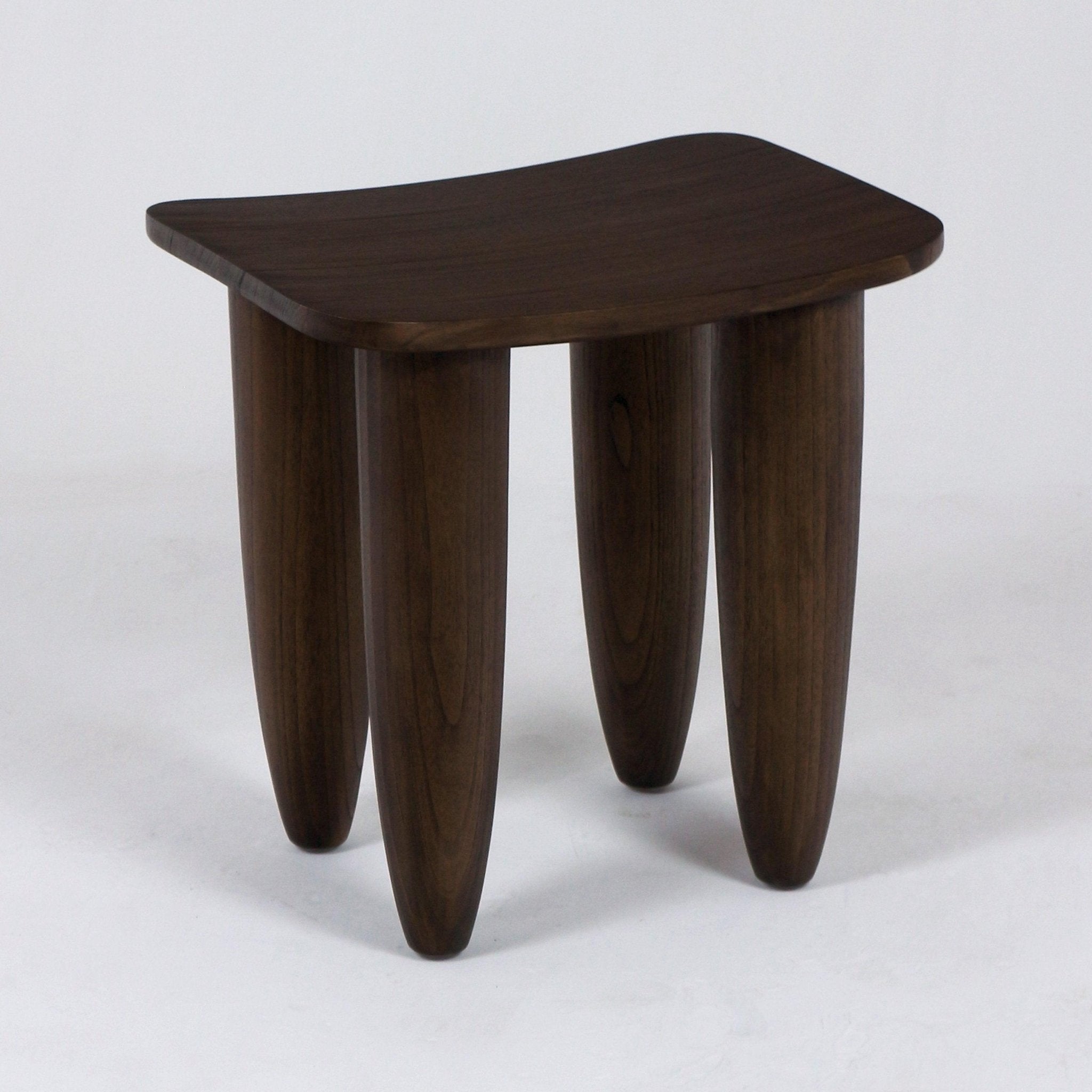 Small modern solid mahogany side table with a gently curved rectangular top and four rounded, tapered legs in a dark mahogany finish on a plain white studio background.