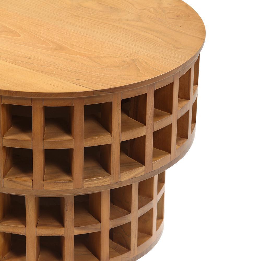 Close-up of a mid-century modern round teak side table with a smooth circular top and stacked lattice of open cubby compartments around the cylindrical base in warm natural teak wood.