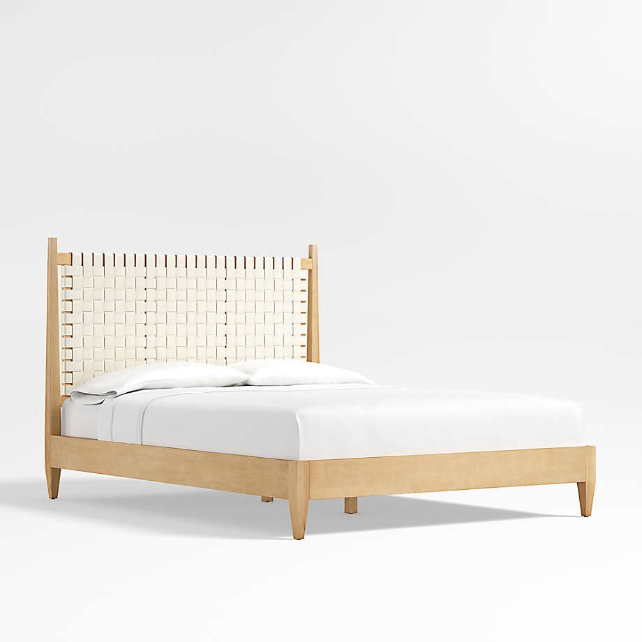 Mid-century modern teak platform bed with a tall woven cream leather headboard, tapered legs and white bedding shown against a clean white background.