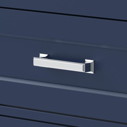 Close-up of a chrome rectangular drawer pull mounted on a deep blue solid wood vanity drawer front with subtle horizontal grooves, reflecting light and reinforcing a glam bathroom aesthetic.