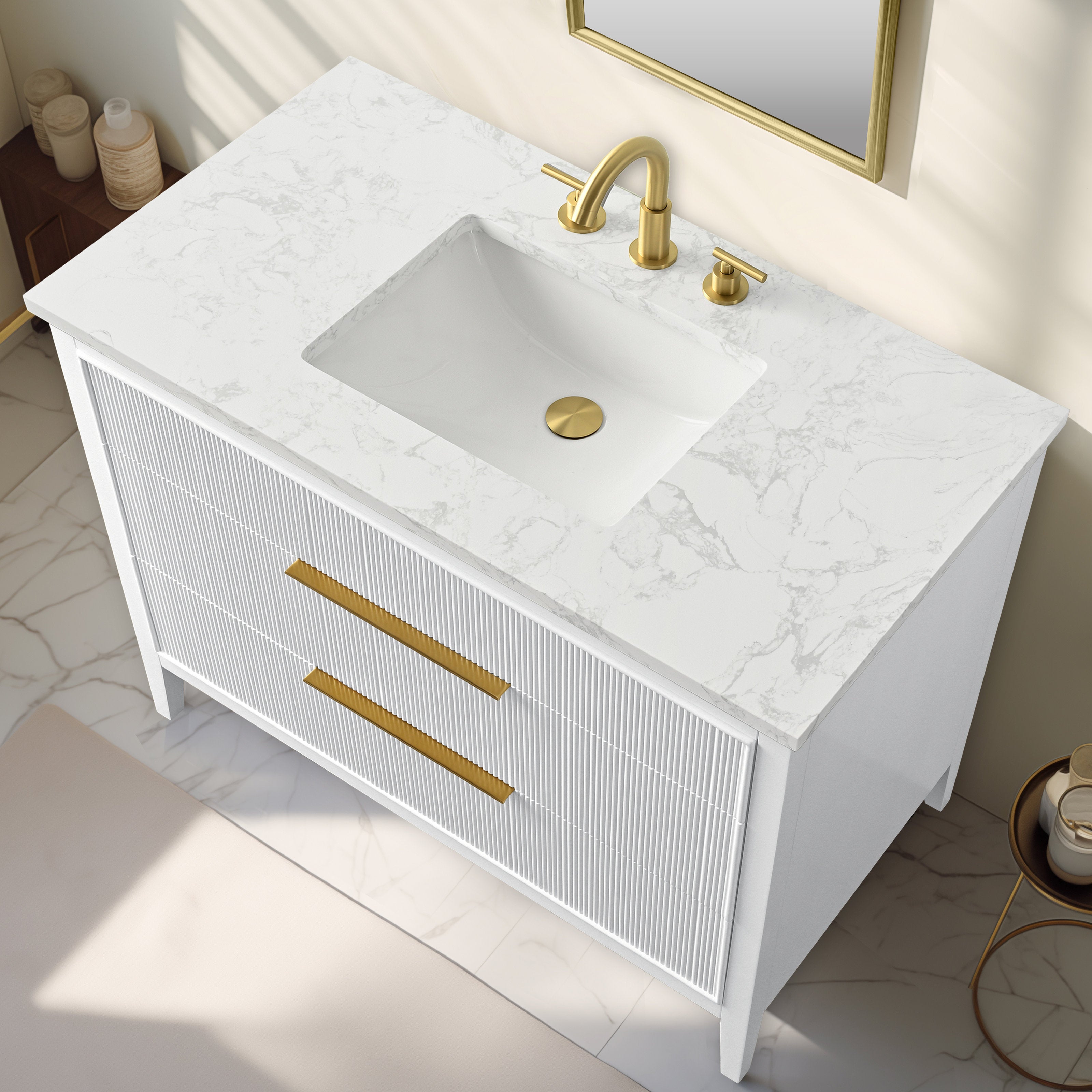 Top-down view of a modern white solid-wood bathroom vanity with a stone-look marble top, rectangular undermount ceramic sink, and brushed gold faucet and matching gold drawer pulls on fluted drawer fronts.