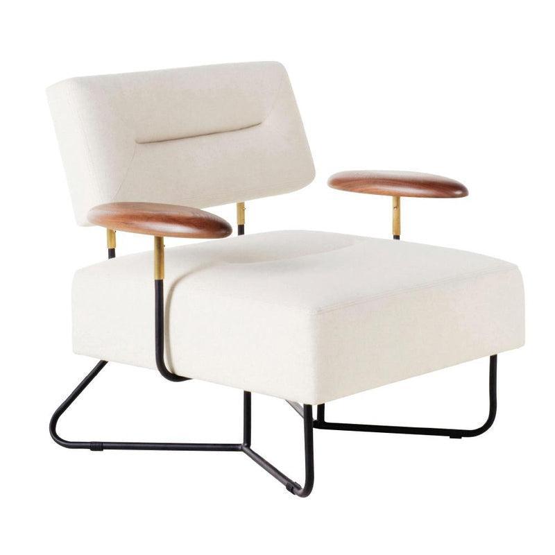 Cream fabric-upholstered lounge chair with a low tufted back and wide square seat, black metal sled base, and walnut wood arm pads mounted on brass supports.