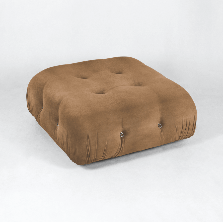 Square tan leather tufted ottoman with deep button tufts, gathered sides and small metal ring accents, photographed on a white studio background.