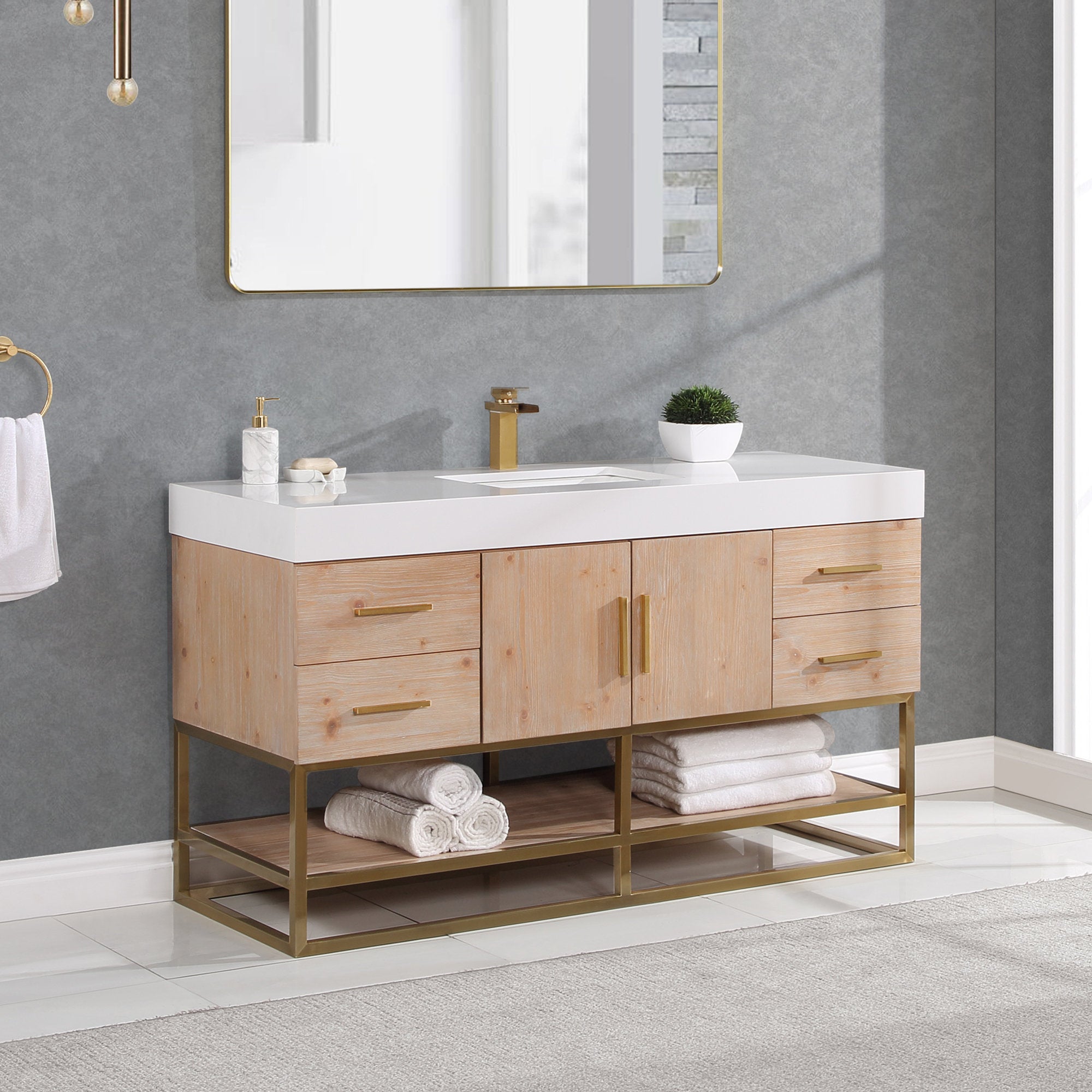 60-inch modern natural wood single-sink bathroom vanity with white composite stone top, rectangular undermount sink and single-hole brass faucet; gold metal base and hardware, open shelf with rolled white towels under a gold mirror.