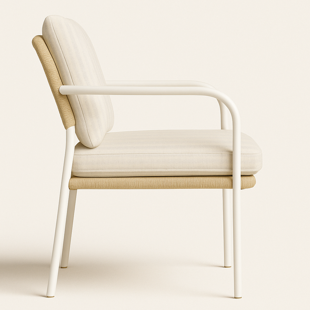 Side profile of a coastal outdoor accent chair with a white aluminum frame, off-white upholstered seat and back cushions, and natural woven wicker-resin trim along the seat and back.